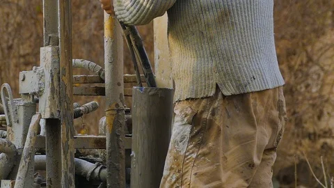 The worker, with his bare hands, pushes a dirty hose into a pipe. Dirt sticks on 스톡 동영상 122324603
