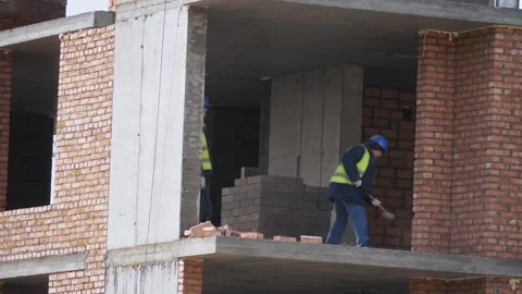 A worker hits a brick wall with a sledgehammer. Dismantling a wall Construction Stock Footage 321004720
