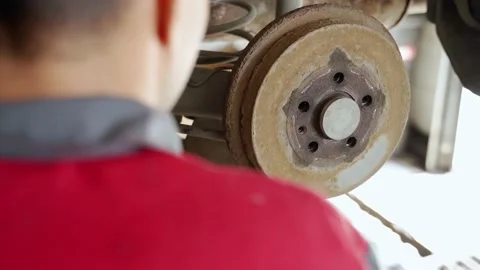 A worker hits an old rusty car brake drum with a hammer, tries to remove it Stock Footage 170880116