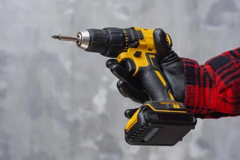 Worker holding cordless drill while wearing protective glove. Concept of cons Stock Photos