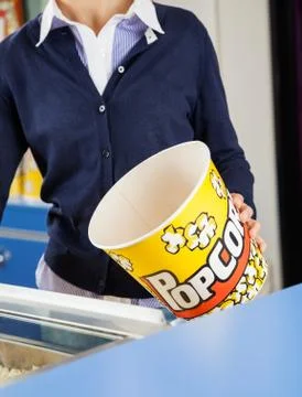 Worker Holding Empty Popcorn Bucket At Concession Stand Foto stock