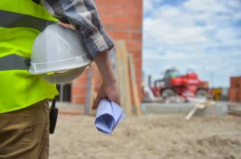 Worker holding a helmet with background of construction site. Stock-Fotos