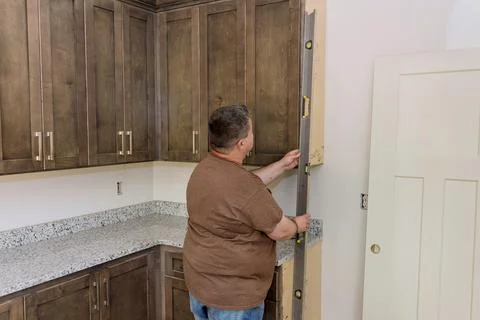 Worker holding a level for the leveling of the new kitchen cabinets before it Stock Photos