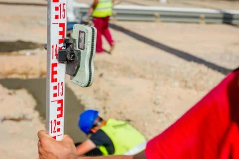 Worker is holding leveling rod to measuring level on construction site Stock Photos