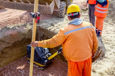 Worker is holding leveling rod to measuring level on construction site Stock Photos