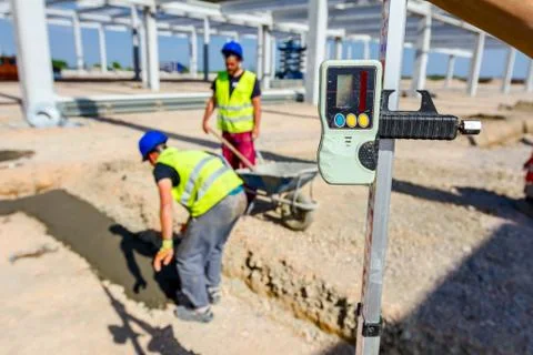 Worker is holding leveling rod to measuring level on construction site Stock Photos