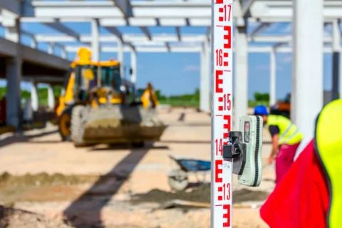 Worker is holding leveling rod to measuring level on construction site Stock Photos