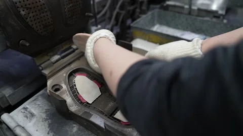 Worker holding a pale rubber midsole blank before laying it into the mold Stock Footage 342897803