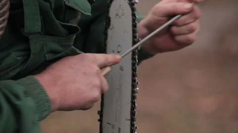 Worker holding sharpener in hand and sharpening blade of the chainsaw. Close up. Stock Footage 46672559