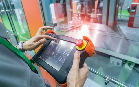 Worker holding smart panel to control automatic robot in ai factory Stock Photos