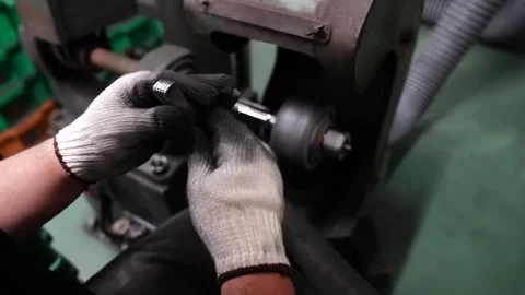 Worker holding stack of stainless steel fork blanks beside spindle polishing Stock Footage 340278813