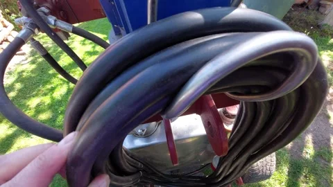 Worker holding a thick black high pressure hydraulic hose coiled on a hook Vídeo Stock 336007114