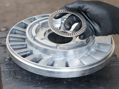 Worker holding a thrust roller bearing above a transmission turbine component Stock Photos