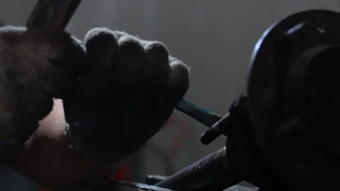 Worker holds a blue metal chisel near a car part. Stock Footage 344230702