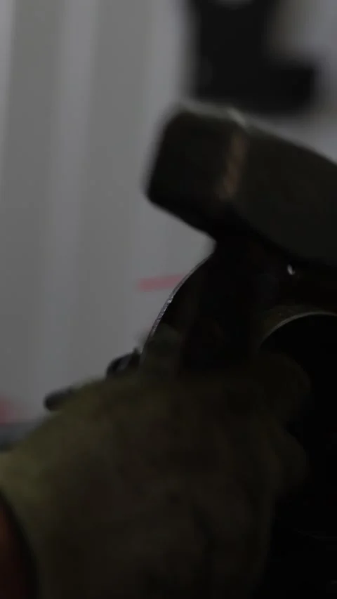 Worker holds a blue metal chisel near a car part. Stock Footage 344230716