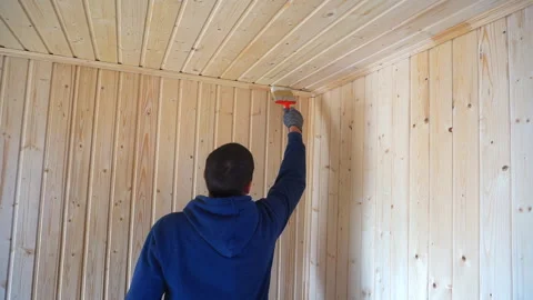 Worker holds a brush and draws a wooden wall, wall cladding, floor or wall surfa Stock Footage 98004624