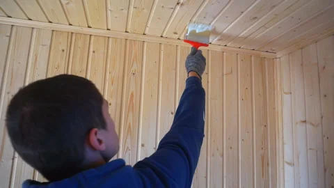 Worker holds a brush and draws a wooden wall, wall cladding, floor or wall surfa Stock Footage 98004655