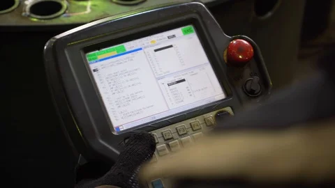 Worker holds control panel of large machine, controls cutting of metal Stock Footage 120064115