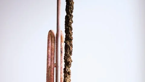 A worker holds a heating element of an electric boiler covered in rust Stock Footage 337251439