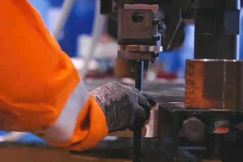 Worker holds a hexagonal key near the machine with his hand. Stock Photos