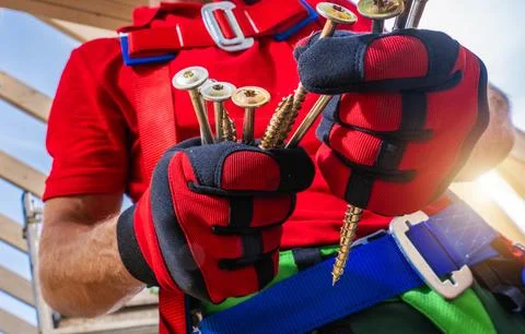 Worker holds screws while working on a construction site in bright sunlight Stock Photos