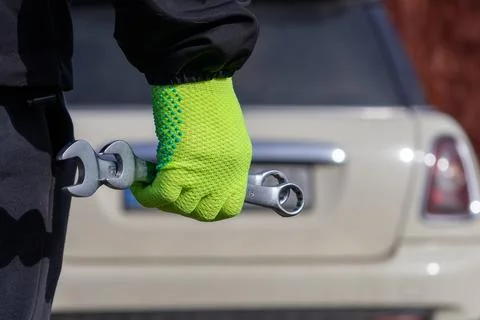 Worker Holds Wrench While Standing Next to Car in a Garage During Daytime, .. Stock Photos