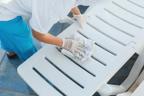 Worker at the hotel removes the water from the deck chairs after the rain Stock Photos