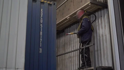 Worker in a huge helmet processes the surface of the container. Stock Footage 105228493