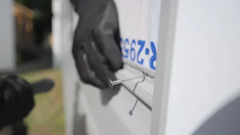 Worker hummers a nail into plastic panel siding on the outside wall of the Stock-Footage 318627662