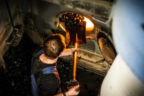 Worker insert a coal inside the engine of coaled power steam ship Stock Photos