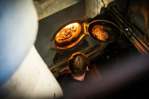Worker insert a coal inside the engine of coaled power steam ship Stock Photos