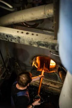 Worker insert a coal inside the engine of coaled power steam ship Stock Photos