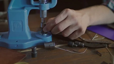Worker insert metal button in belt. Leather accessories manufacturing Stock Footage 84939842