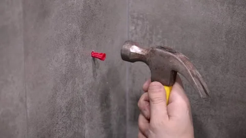 Worker inserts red plastic wall plug with hammer 库存影片 304120093