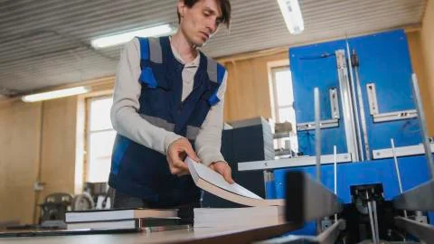 Worker inserts sheets of paper to printing machine, polygraph industry Stock Photos
