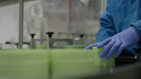 Worker inspecting cosmetic boxes on conveyor belt in factory Stock Footage 107956826