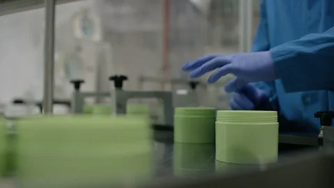Worker inspecting cosmetic boxes on conveyor belt in factory Stock Footage 107956861