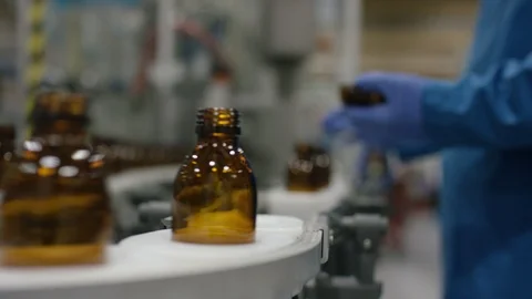 Worker inspecting empty bottles on production line in cosmetic factory Video stock 107979202