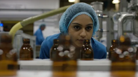 Worker inspecting empty bottles on production line in cosmetic factory Stock Footage 107986727