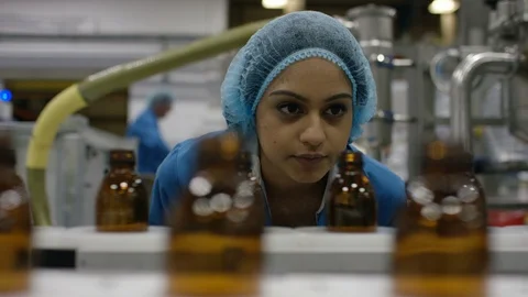 Worker inspecting empty bottles on production line in cosmetic factory Stock Footage 107987069