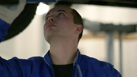 The worker inspects the bottom of the car with a lantern. Stock Footage 80469937