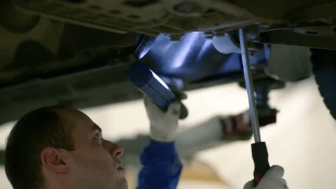 The worker inspects the bottom of the car with a lantern. Stock Footage 80469941