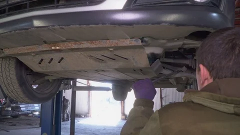 Worker inspects a car chassis on car lift Video stock 106138296