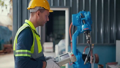 Worker inspects robot arm with handheld device Video stock 341315280