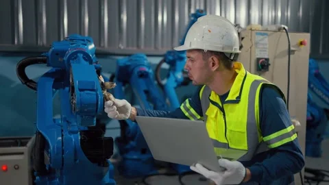Worker inspects robotic arm with laptop Video stock 341315248