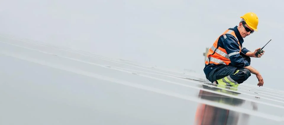 Worker inspects solar panels during daylight at renewable energy site while.. Stock Photos