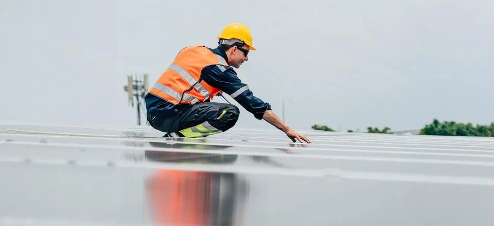Worker inspects solar panels during daytime at a renewable energy site Stock Photos