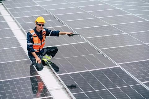 Worker inspects solar panels on a rooftop in a sunny outdoor environment in.. Stock Photos