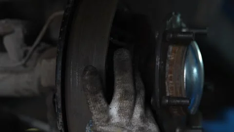 Worker inspects the underside structure of a car chassis wheel. Stock Footage 344229924