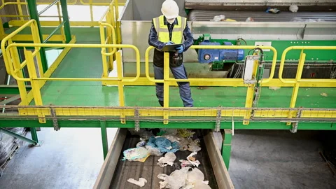 Worker inspects waste materials at recycling facility during operational hours Stock Footage 301719834